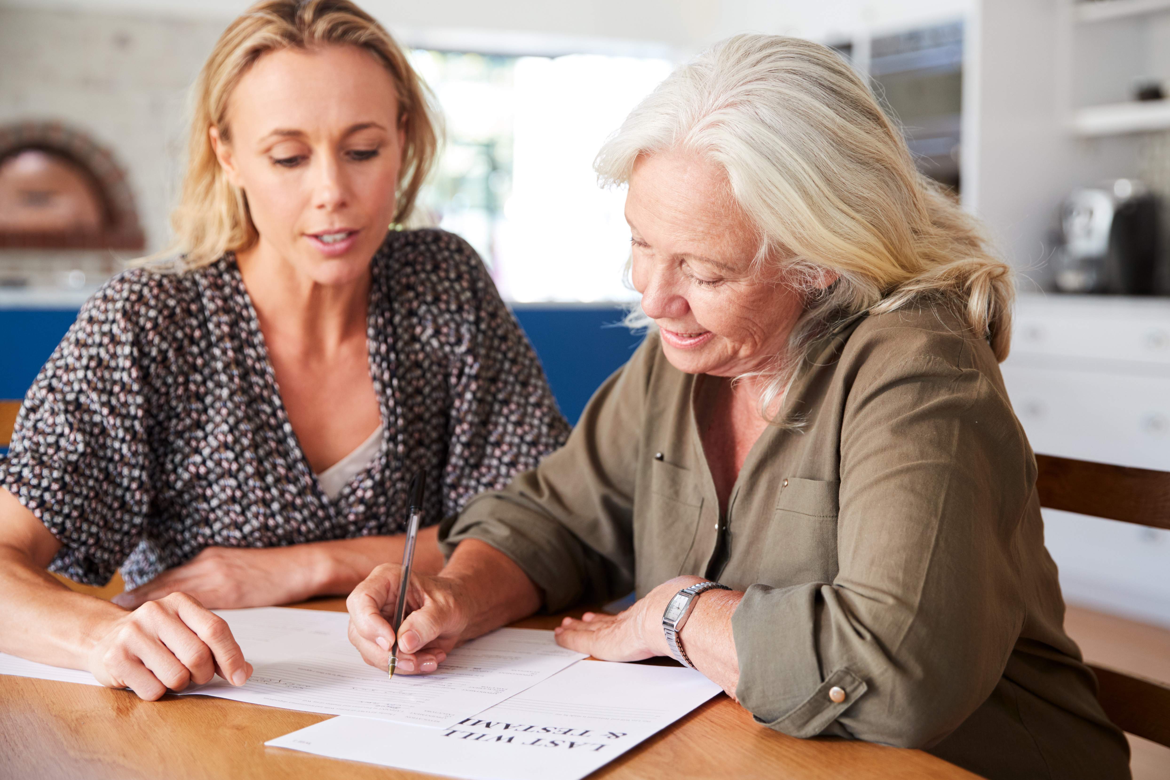 Two women seated at a table, looking at paperwork together. Based on blog content, the paper is about wills and/or trusts. 