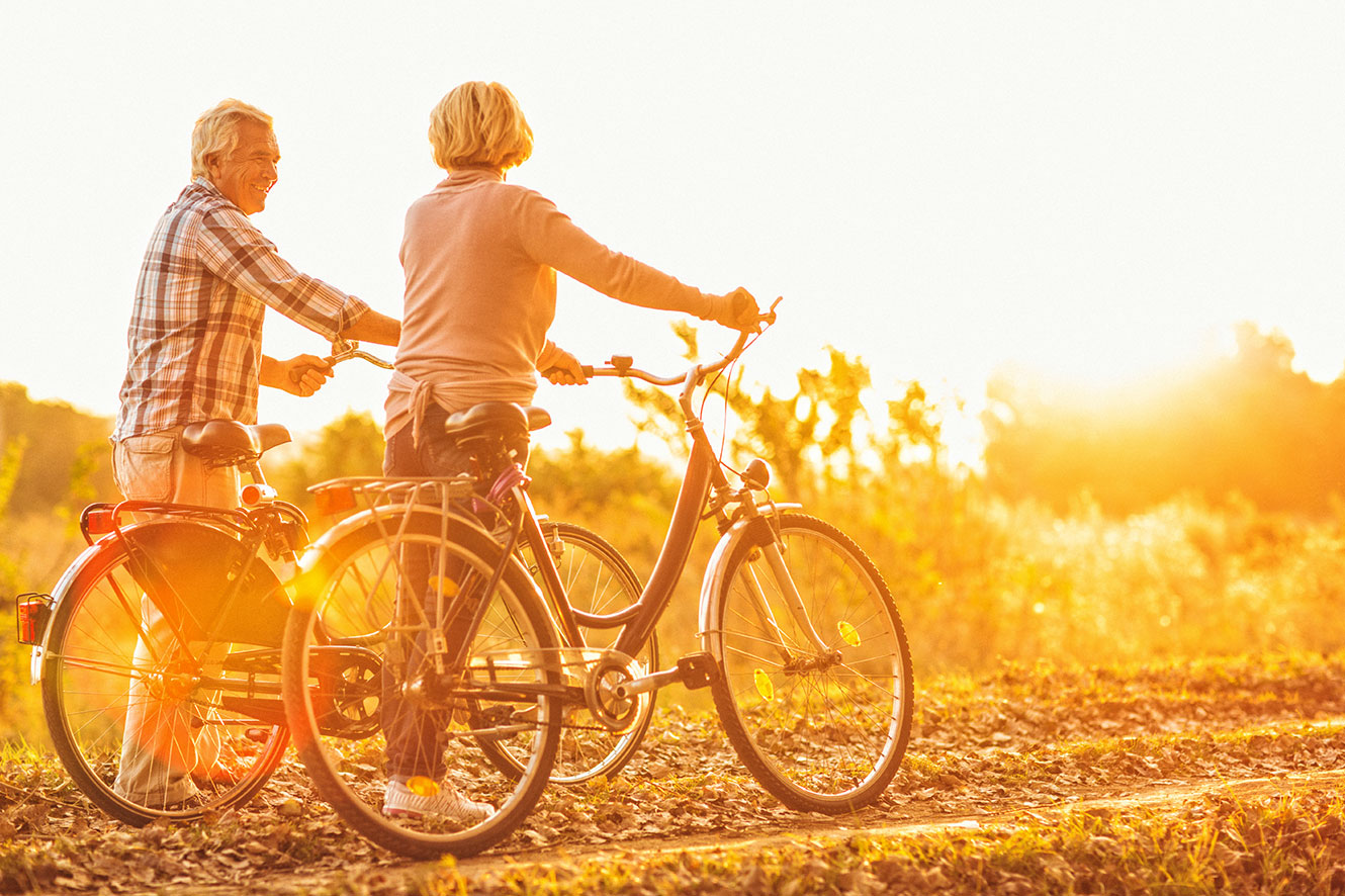 An older couple standing next to their bikes during golden hour